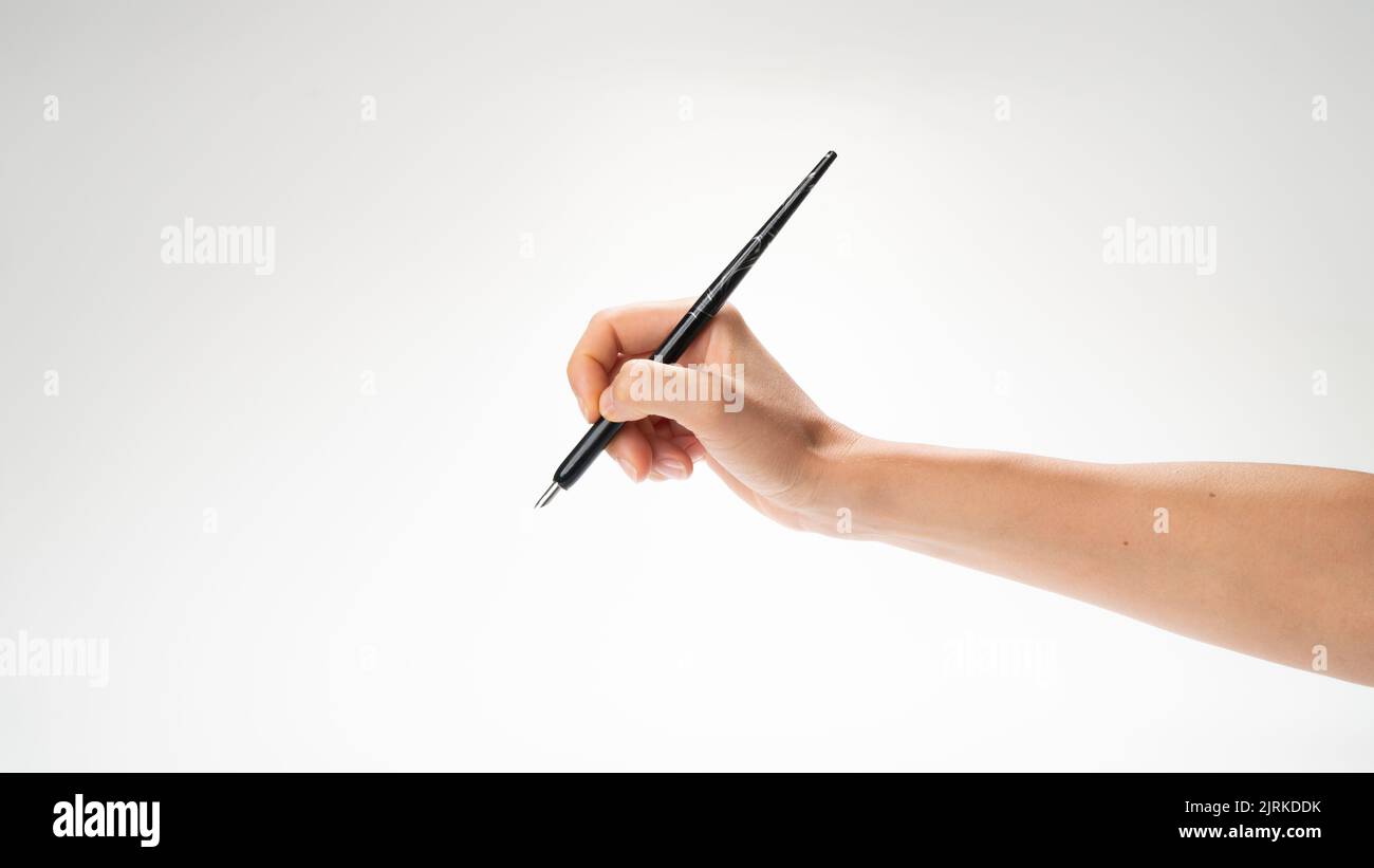 La mano destra di una donna tiene una penna per calligrafia e gesto di scrittura per scrivere. Foto di alta qualità Foto Stock