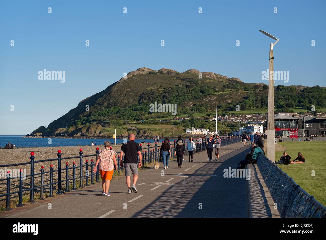 Persone che camminano lungo la passeggiata sul lungomare in una soleggiata giornata estiva a Bray, Co. Wicklow, Irlanda. La montagna Bray Head sullo sfondo. Foto Stock