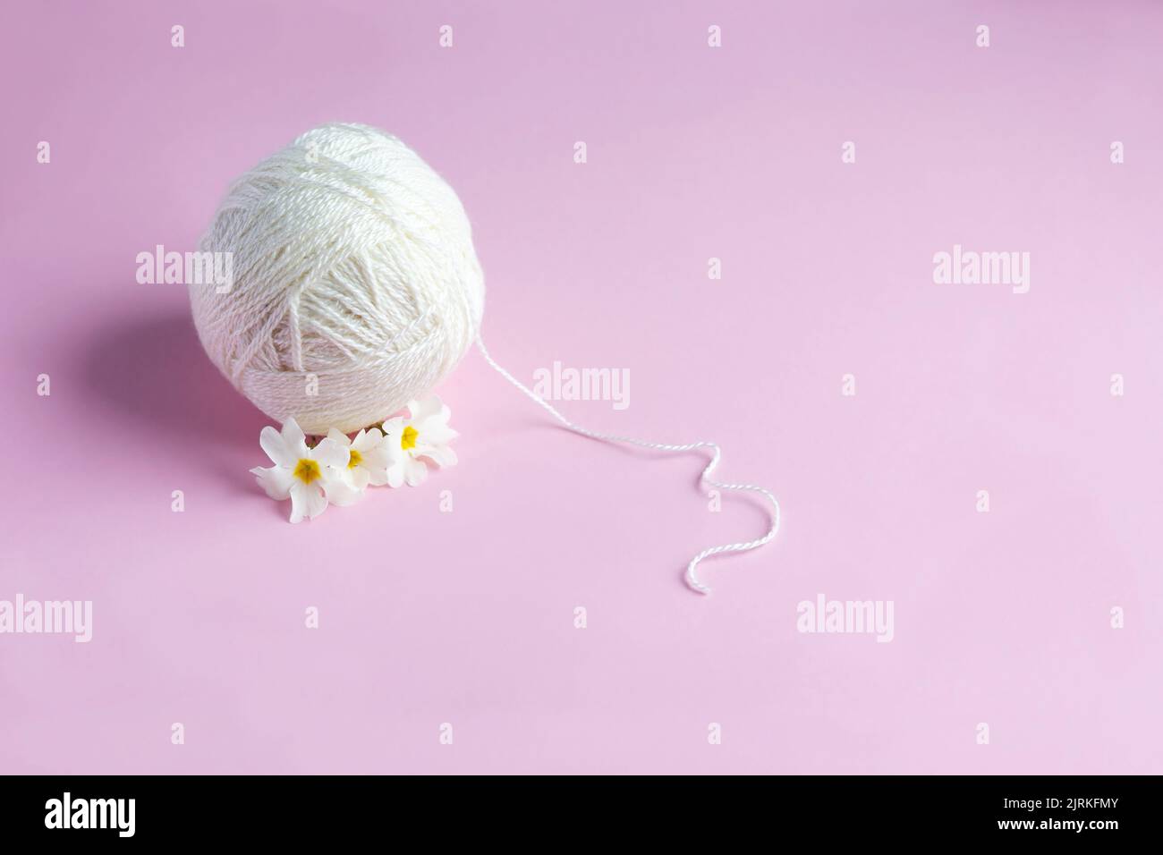 Palla bianca di filo su sfondo rosa. Lavorazione a maglia hobby Foto Stock