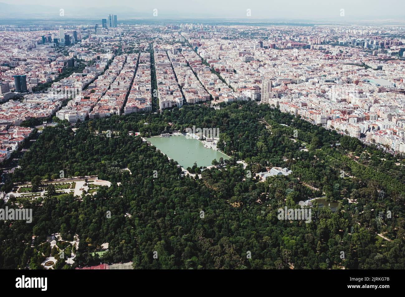 Dall'alto drone vista panoramica della città con densa infrastruttura con lago e parco a El Retiro a Madrid, Spagna Foto Stock