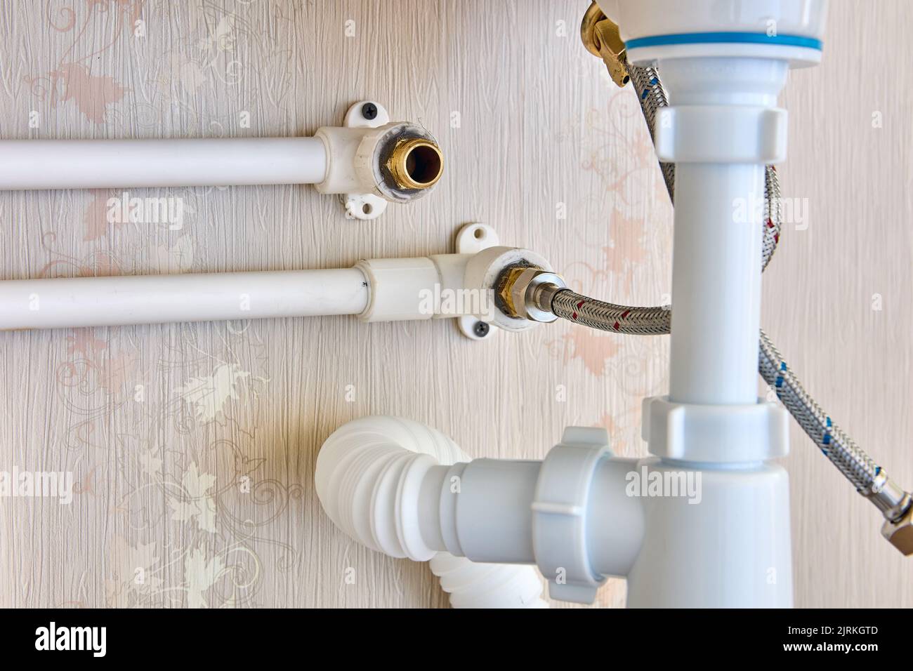 Collegamento del rubinetto al sistema di alimentazione dell'acqua domestica mediante un tubo in acciaio inossidabile intrecciato. Foto Stock