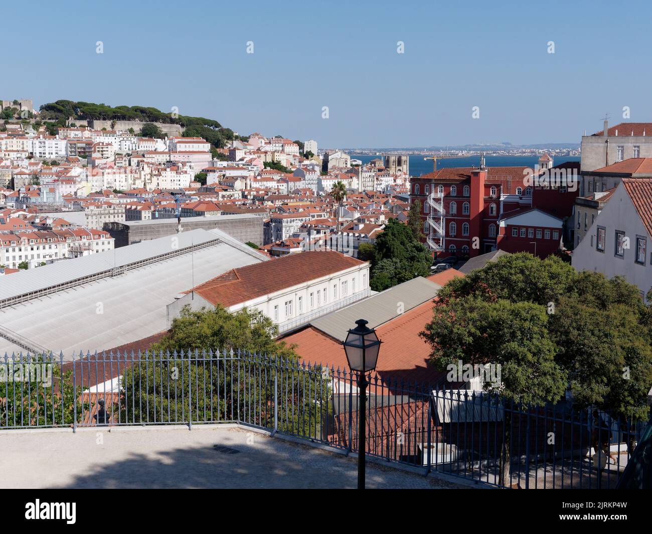 Vista dal punto di vista (Miradouro) São pedro de Alcântara a Lisbona Portogallo in una serata estiva sui tetti della città. Fiume Tago a destra. Foto Stock
