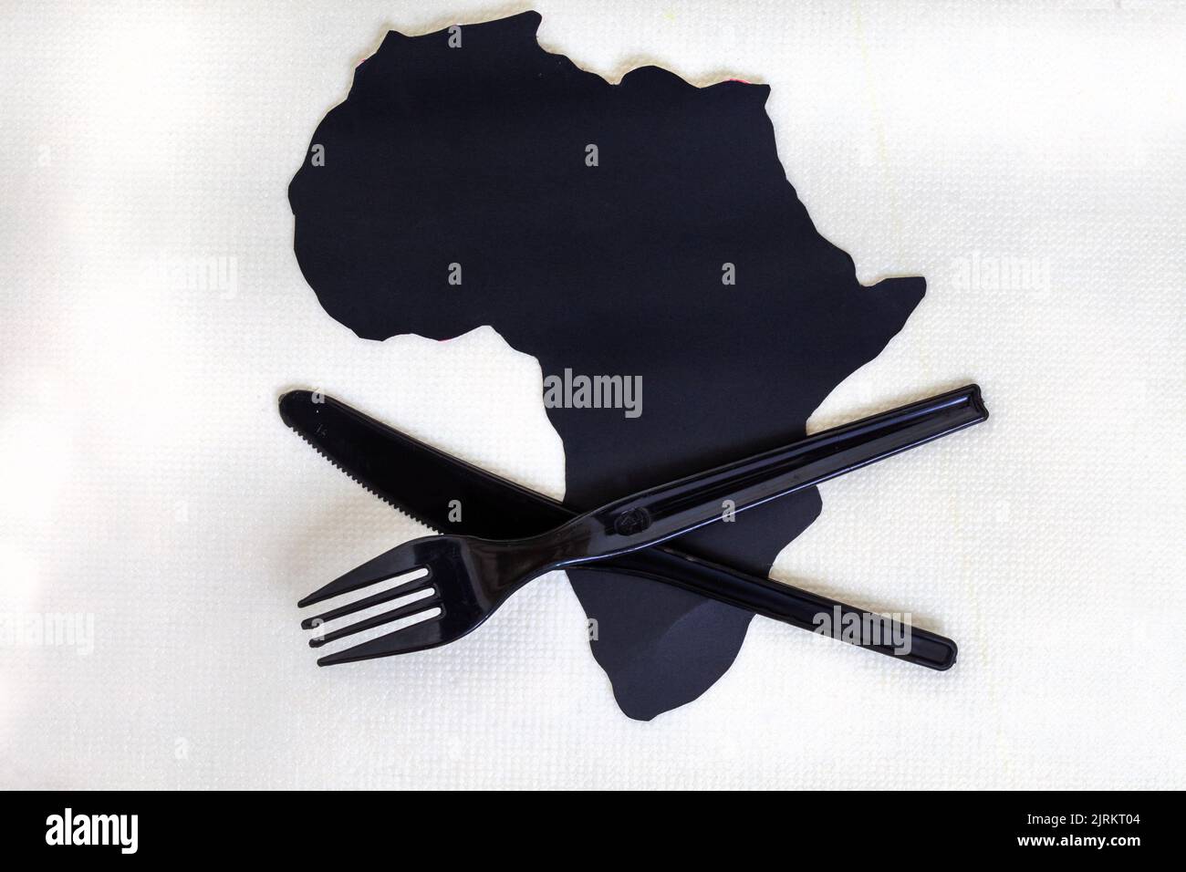 Taglio nero del continente africano su bianco con posate di plastica e spazio copia Foto Stock