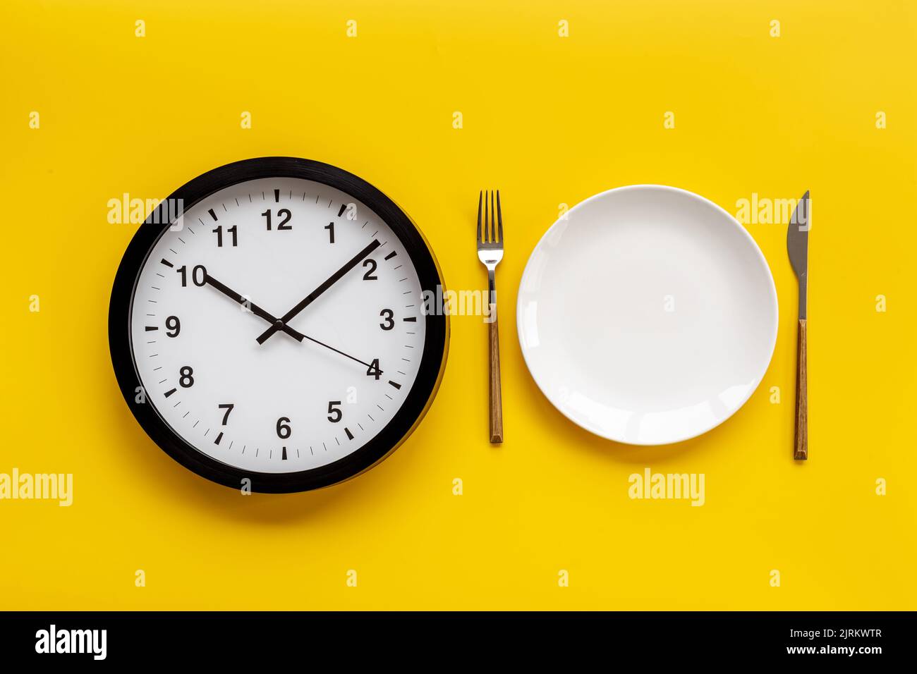 Tempo di mangiare - concetto di tempo di pasto. Orologio da parete rotondo con piastra Foto Stock