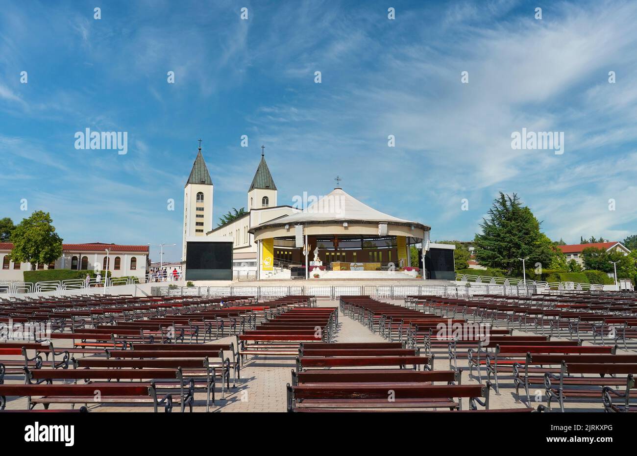 L'area dietro la chiesa parrocchiale di San Giacomo a Međugorje (o Medjugorje) con il grande altare e la spianata di panchine per i fedeli Foto Stock