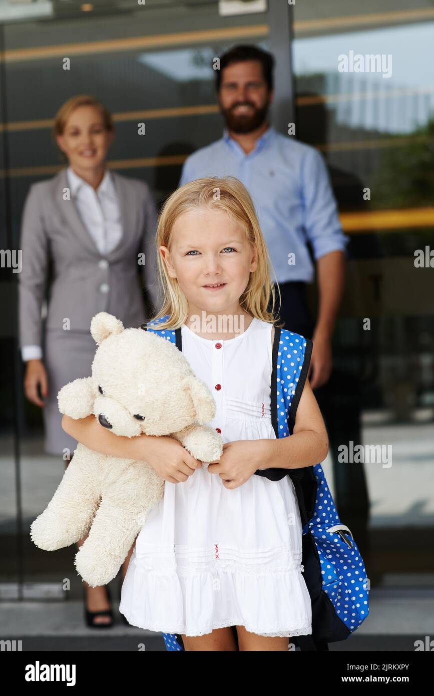 Allegra bambina con zaino e orsacchiotto il suo primo giorno di scuola Foto Stock