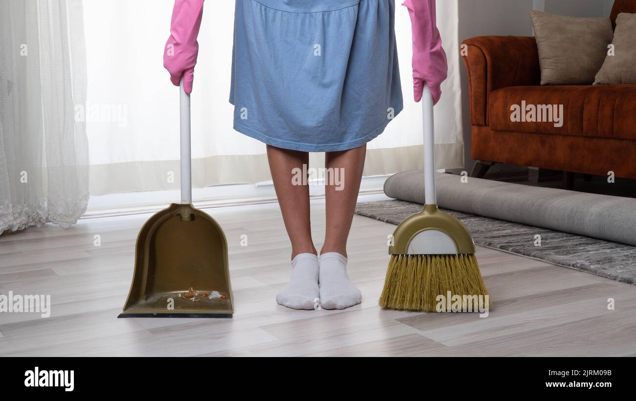 una donna con guanti di gomma rosa con scopa e paletta Foto Stock