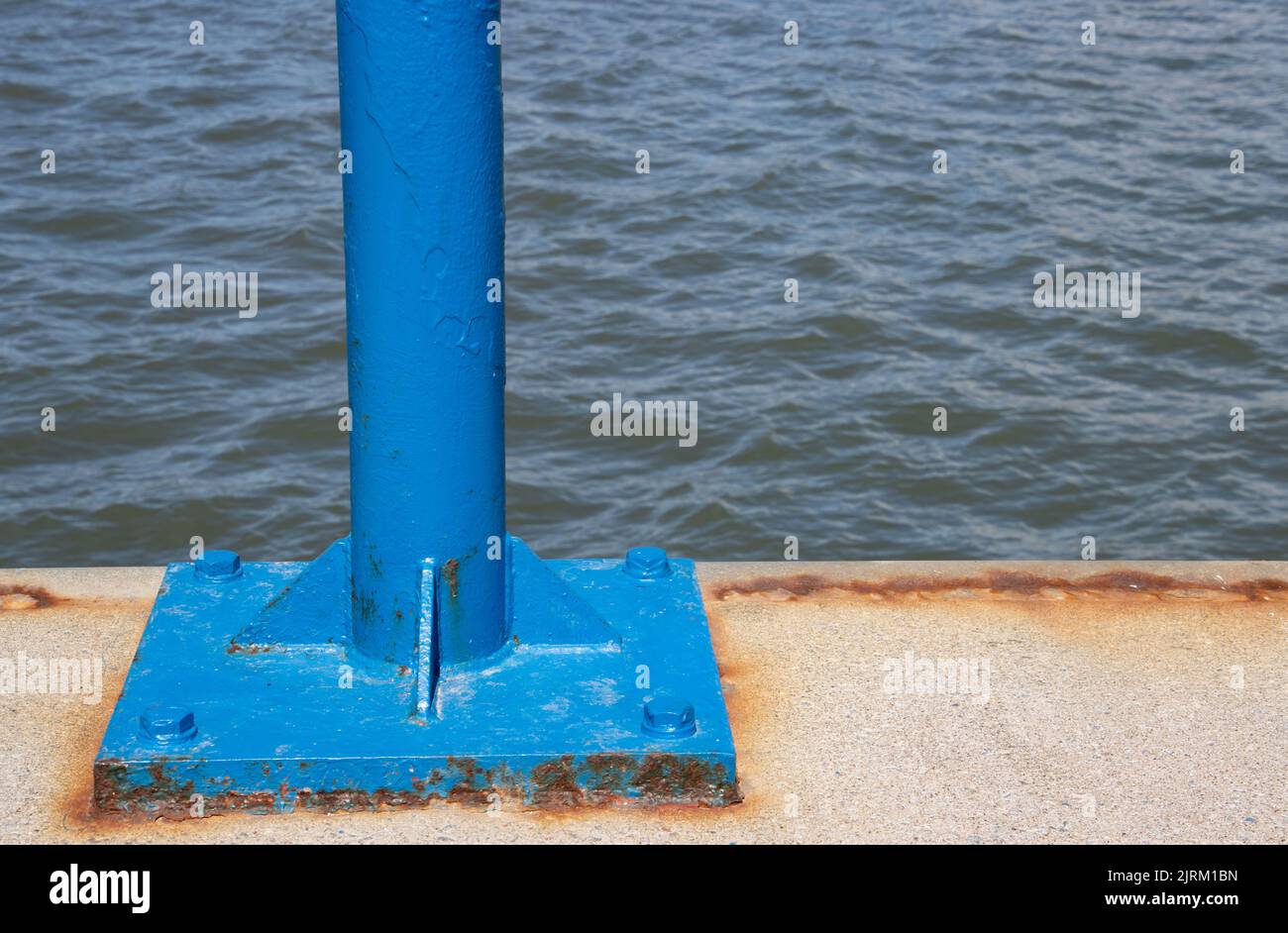 Palo blu in un molo con acqua sullo sfondo e spazio di copia Foto Stock