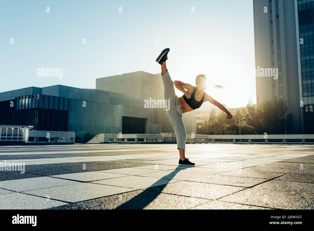 Donna che pratica le arti marziali all'aperto. Atleta femminile che pratica calcio in città. Foto Stock