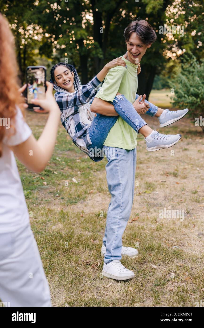 Ragazza caucasica utilizzando il telefono cellulare registrazione di un video di due persone che ballano per pubblicare su Internet applicazione. Tendenze dei social network. Applicazione comune Foto Stock