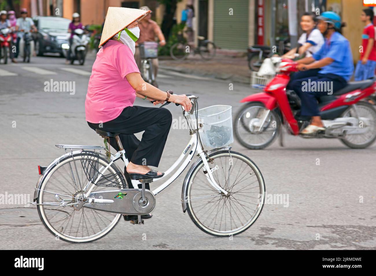 Signora vietnamita che indossa un cappello di bambù in bicicletta, Hai Phong, Vietnam Foto Stock