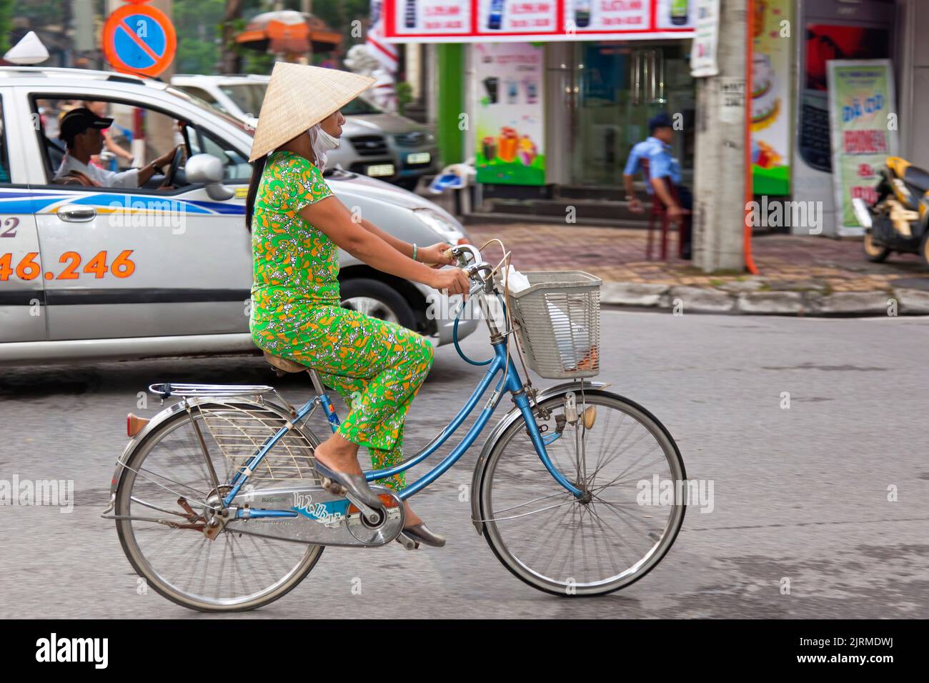 Signora vietnamita che indossa un cappello di bambù in bicicletta, Hai Phong, Vietnam Foto Stock