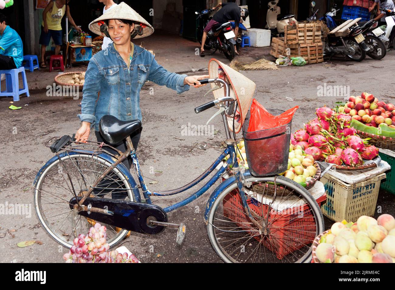 Signora vietnamita che indossa un cappello di bambù in bicicletta, Hai Phong, Vietnam Foto Stock