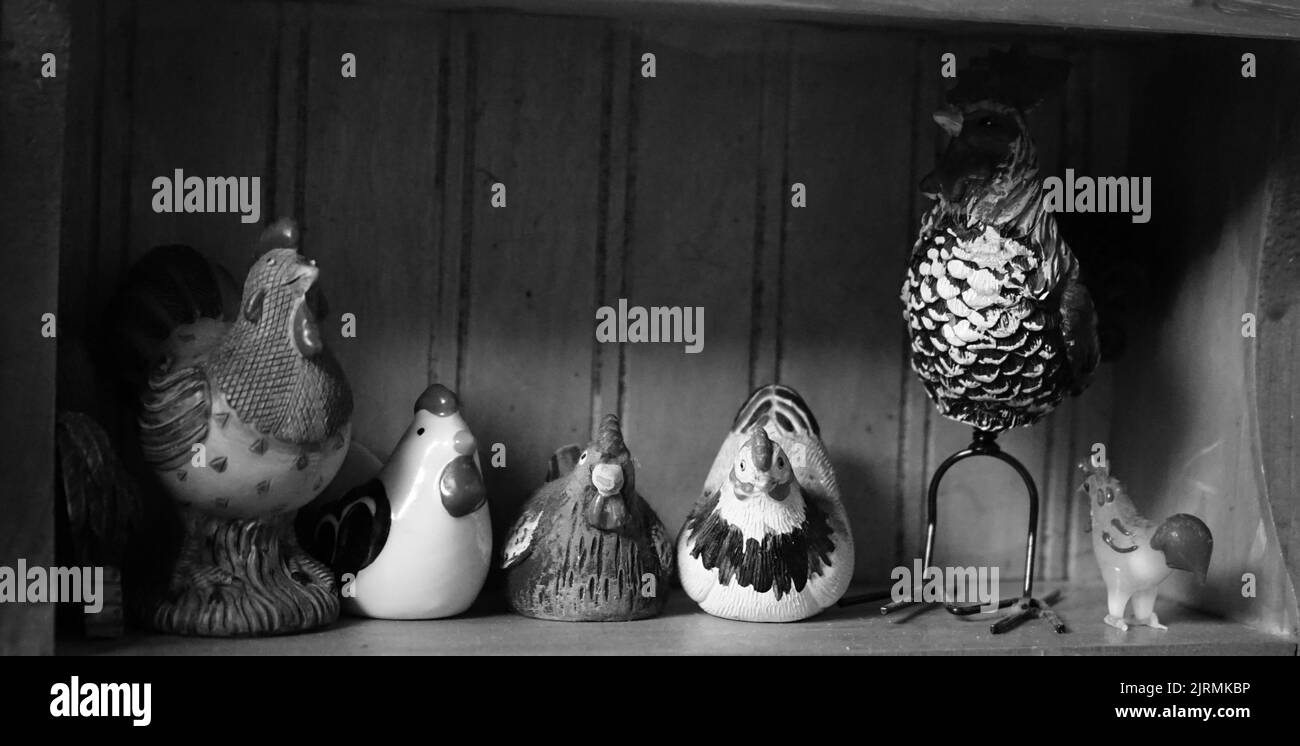 Una foto in scala di grigi di graziosi animali in ceramica realizzati all'interno di una mensola Foto Stock