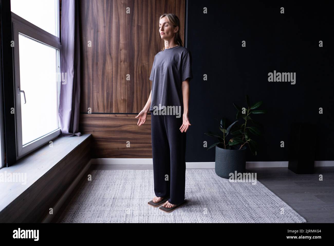 Una giovane donna pratica in piedi su tavole con chiodi. Foto Stock