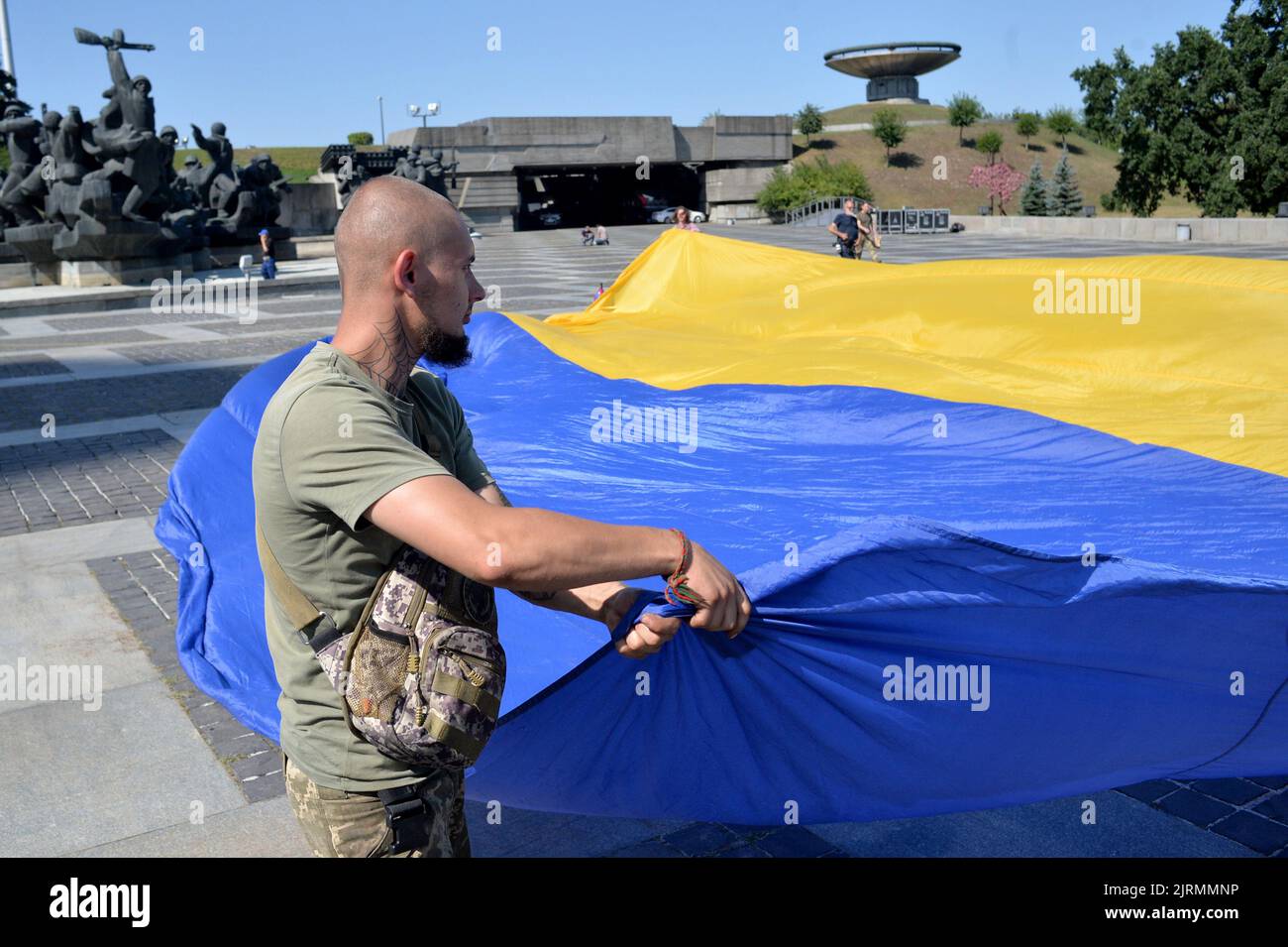 KIEV, UCRAINA - 24 AGOSTO 2022 - Un uomo dispone la bandiera dell'Ucraina sul terreno come i preparativi per sollevare le bandiere di brigate da combattimento dell'Arm Foto Stock