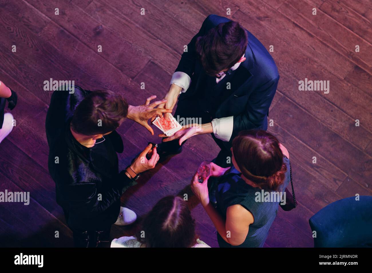 il mago mostra i trucchi delle carte degli ospiti nella vista dall'alto della festa. Foto Stock