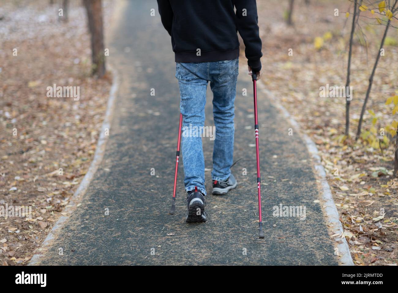 Il giovane cammina con bastoni nordici scandinavi. Stile di vita sano Foto Stock