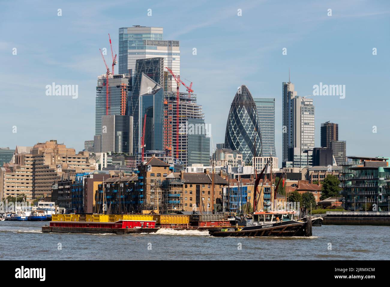 Cory recupero ambientale Tug tirando carico chiatta sul fiume Tamigi. Londra, Regno Unito. Traffico fluviale per l'industria. Skyline del quartiere finanziario di Londra Foto Stock