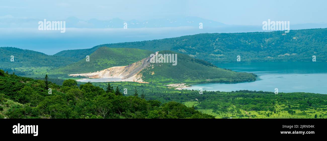 Paesaggio di Isola di Kunashir, laghi e cupole laviche nel centro del vulcano Golovnin caldera; l'isola di Hokkaido è visibile in lontananza nel Foto Stock