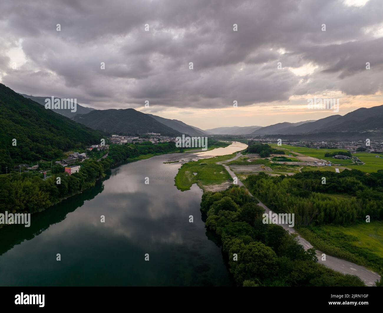Il fiume scorre attraverso la valle rurale e le piccole città dopo il tramonto Foto Stock