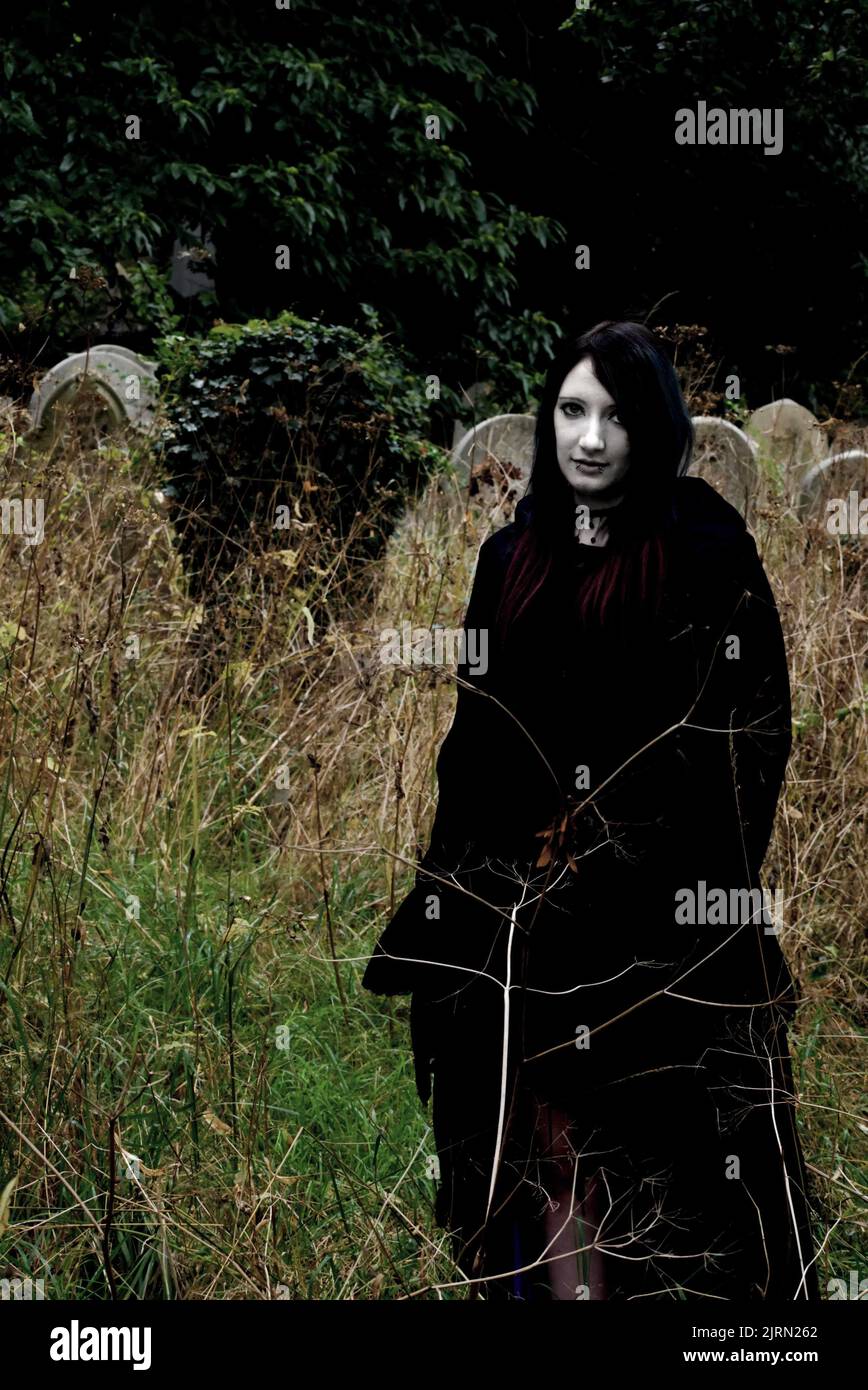 Le donne pallido e spoky di fronte in nero in piedi in un cimitero. Halloween, immagine spettrale della copertina del libro. Foto Stock