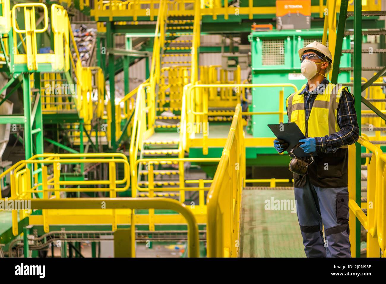 Caucasian City Trash struttura di smistamento lavoratore nel suo 40s indossare occhiali di sicurezza e un Hardhat. Settore della gestione dei rifiuti. Foto Stock