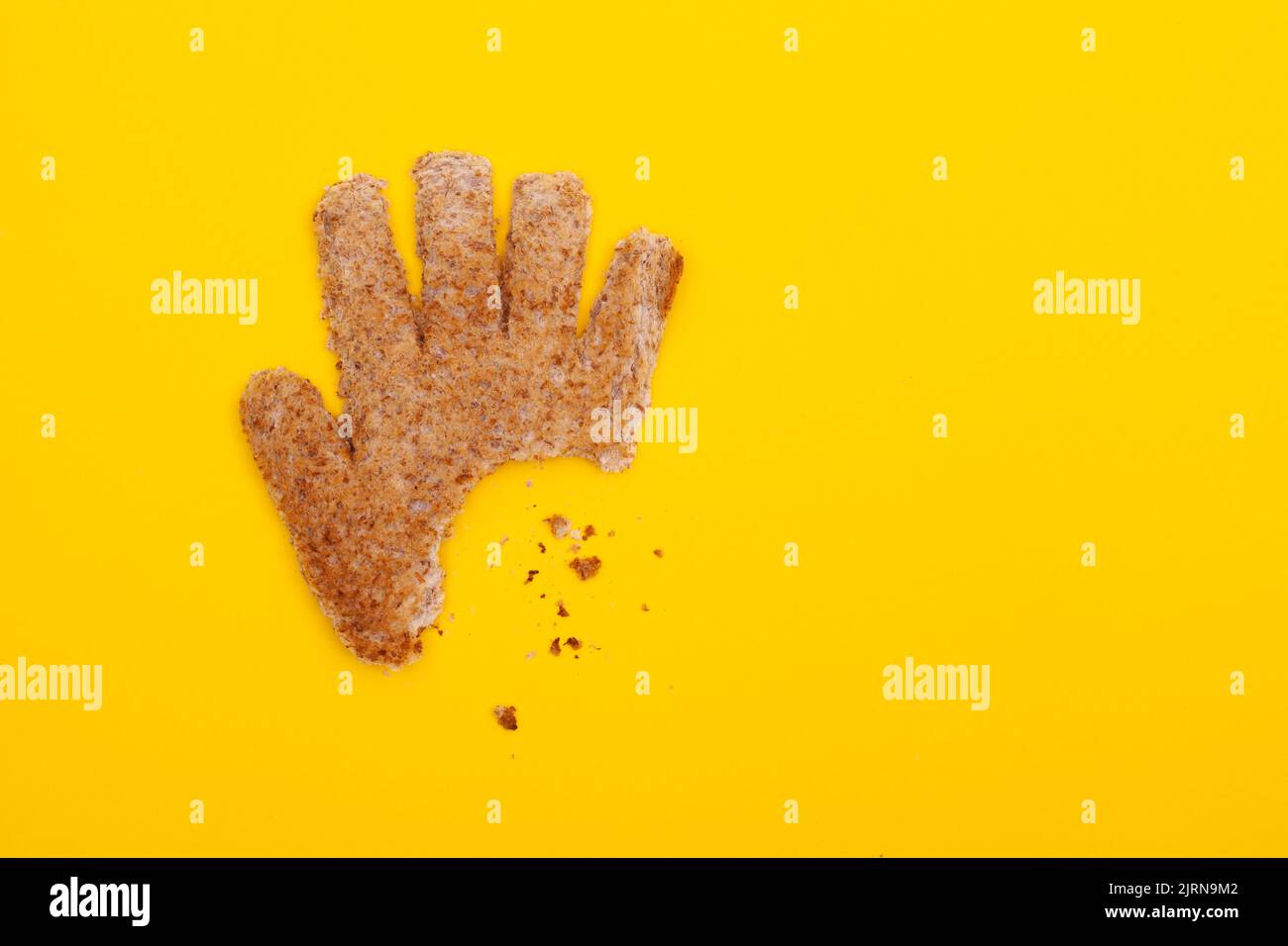 Mordete la mano che alimenta il concept a base di pane tostato a forma di mano Foto Stock