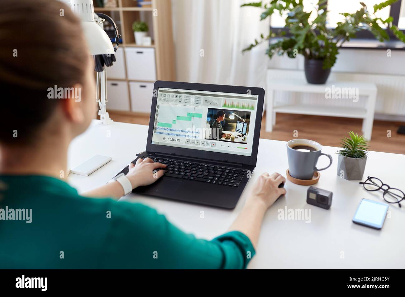 donna con video editor programma sul portatile a casa Foto Stock
