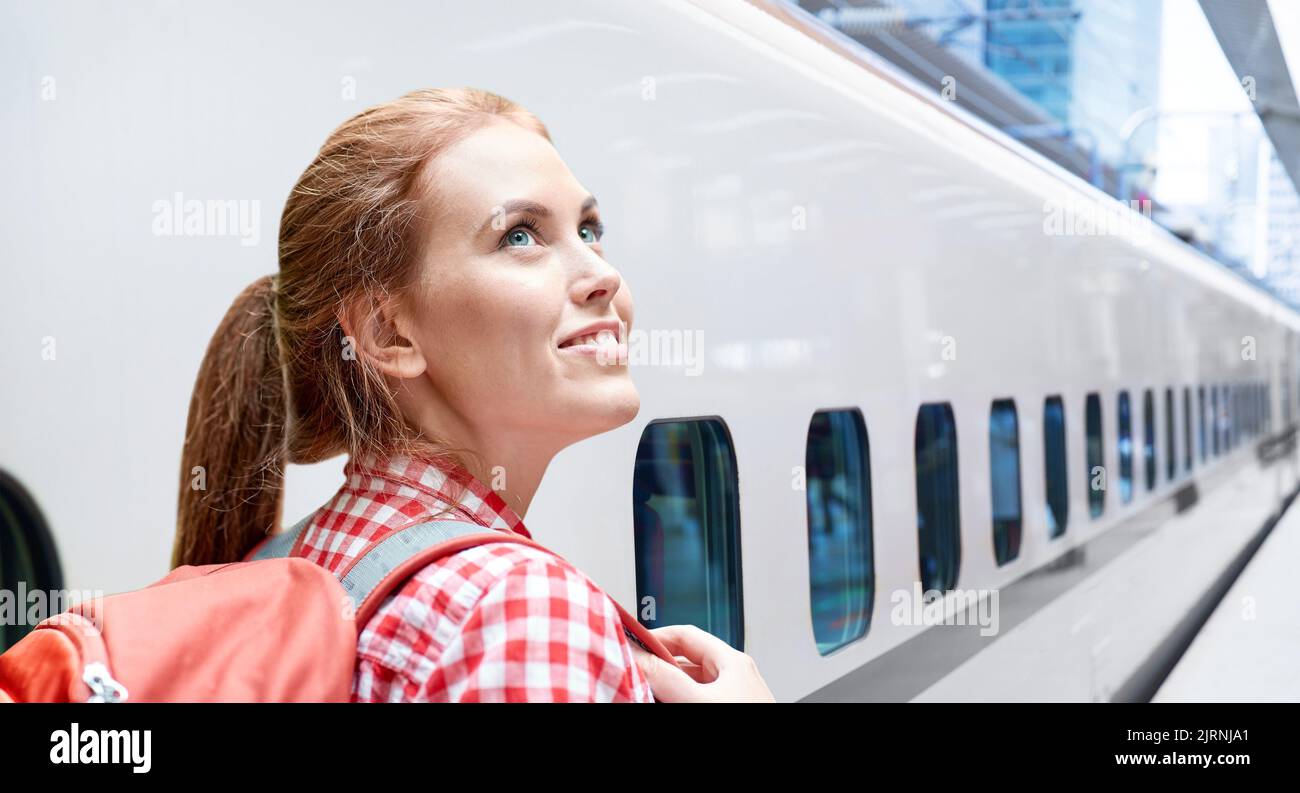 donna sorridente con zaino in viaggio sul treno Foto Stock