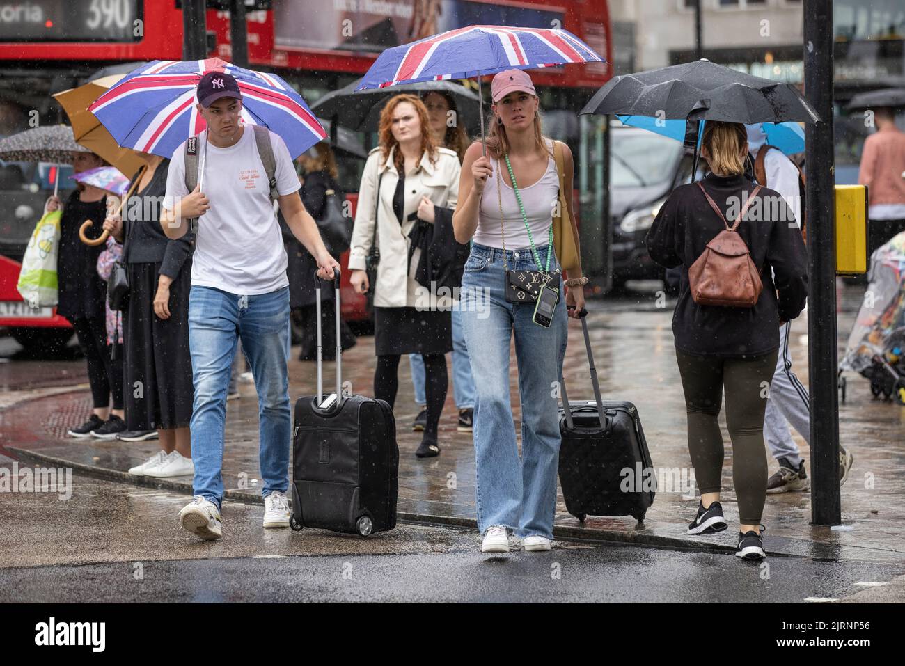 Pendolari e turisti sfidano le torrenziali docce estive a pioggia a Oxford Street a Londra dopo una mini-ondata di caldo e settimane di clima secco sul Regno Unito. Foto Stock