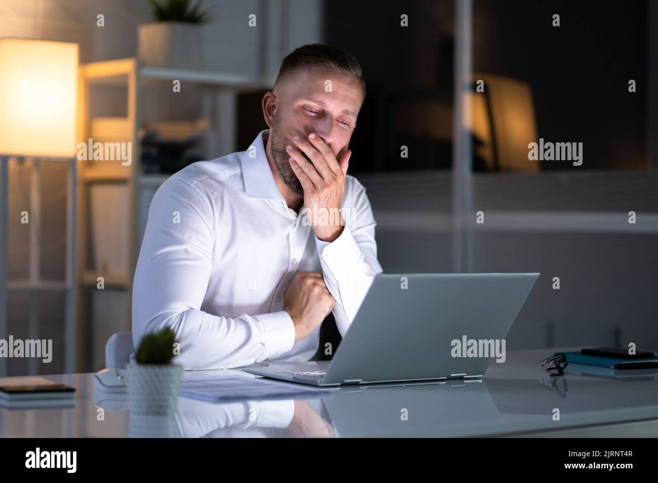 Annoiato uomo di notte sbadiglio guardando il computer Foto Stock