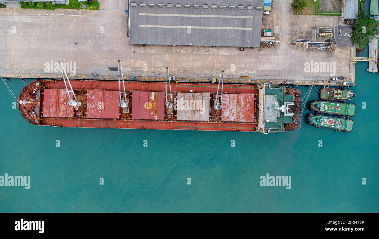 Vista aerea dal drone di una nave commerciale con gru durante lo scarico dei container verso una grande nave commerciale nel molo. Trasporto e viaggio di ritorno Foto Stock