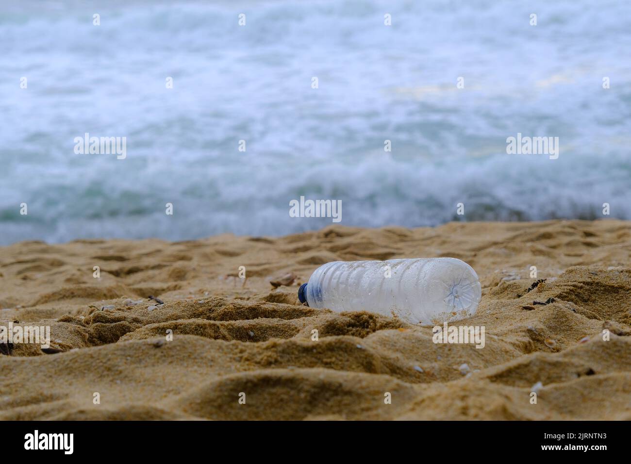 Bottiglia d'acqua di plastica sulla spiaggia. Concetto di inquinamento plastico e problemi ambientali Foto Stock
