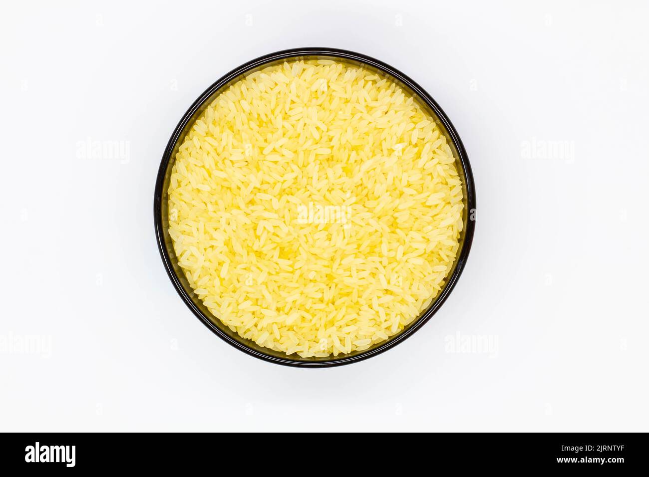 Un piatto di riso. Ciotola nera con grani di riso bianco su fondo bianco. Cibo sano. Riso bianco crudo macinato che ha avuto buccia, crusca, germe Foto Stock