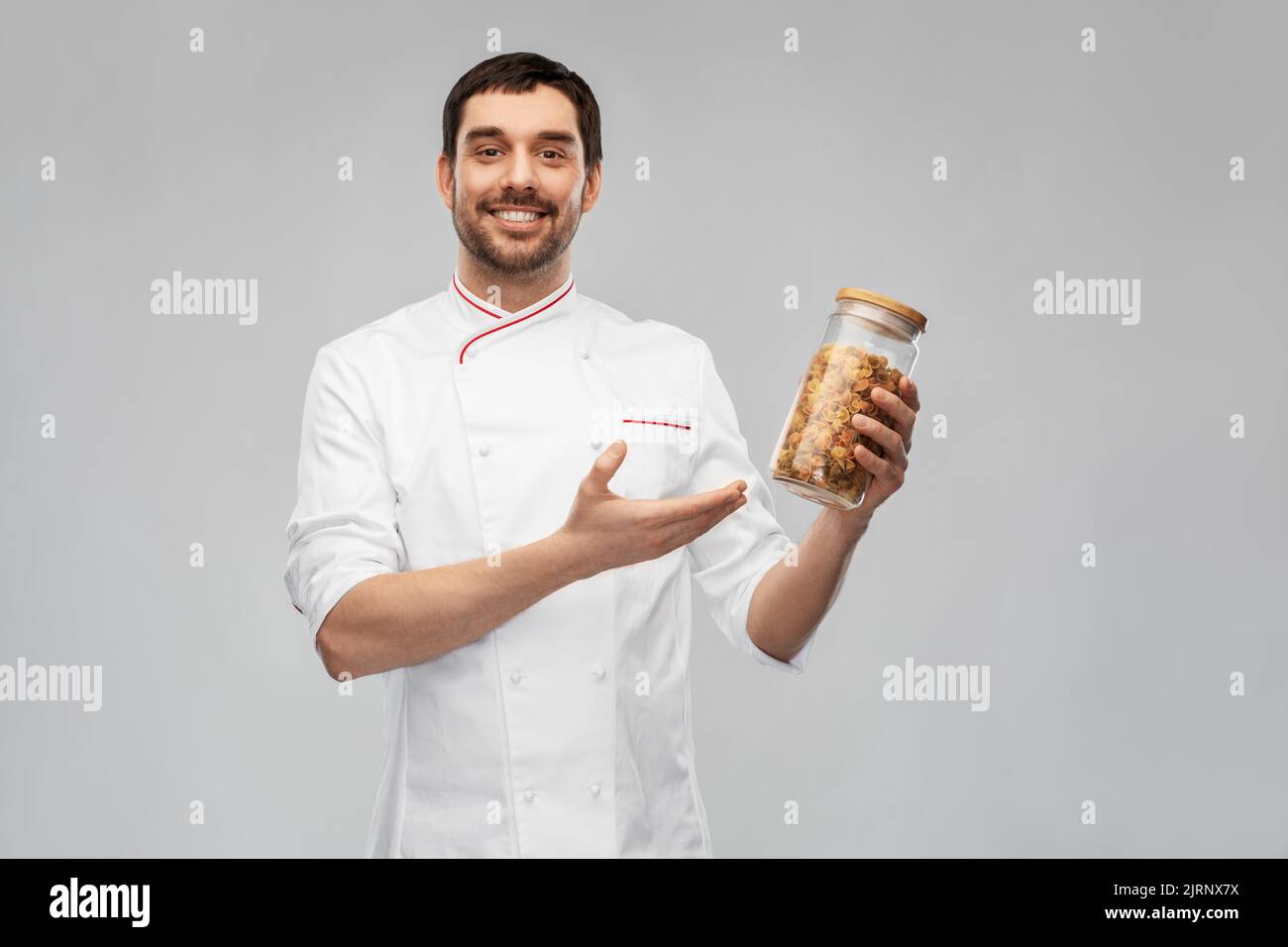 buon chef sorridente con pasta in vaso di vetro Foto Stock