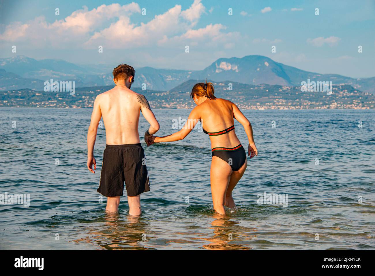 Felice giovane coppia turistica in luna di miele fate un tuffo nella romantica Sirmione, sul Lago di Garda, Brescia, Italia Foto Stock