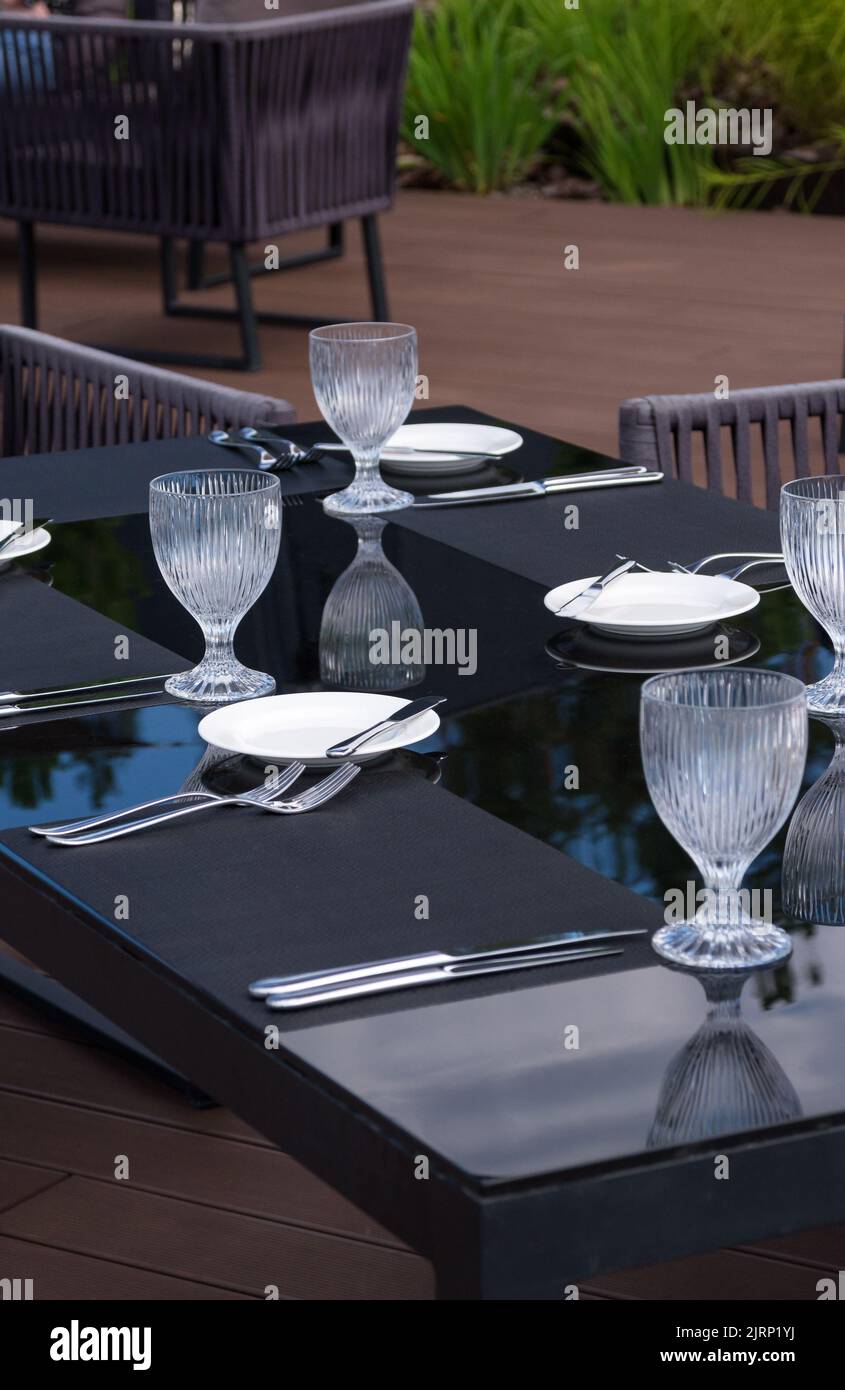 Bicchieri vuoti di cristallo, piatti bianchi e posate su un tavolo in un ristorante sulla spiaggia. Tavolo per una cena di festa. Foto Stock