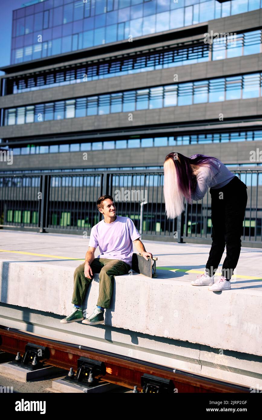 Una felice coppia adolescente è seduta alla stazione ferroviaria e scatta foto. Foto Stock