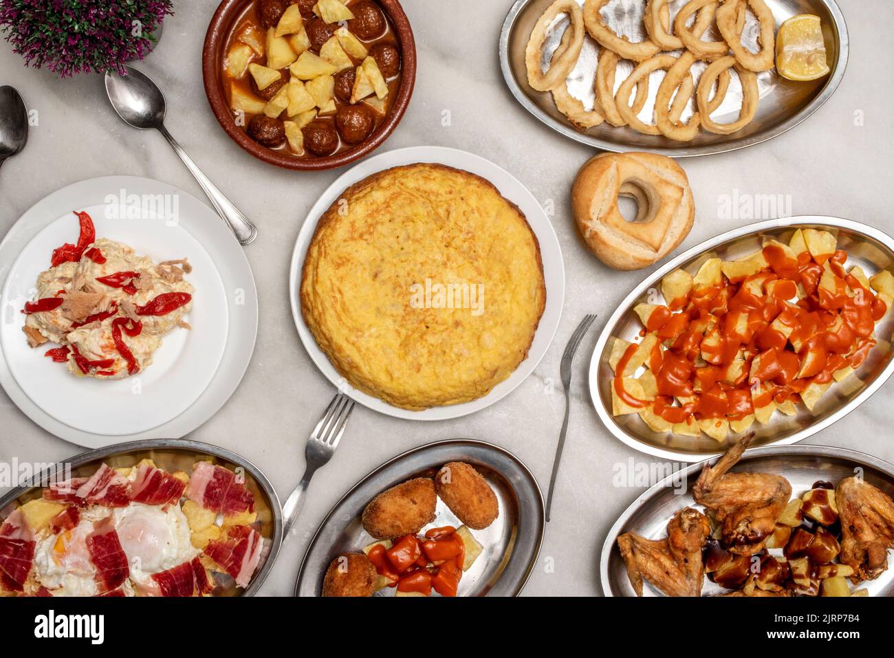 Set di piatti deliziosi e tapas di cibo spagnolo, frittata di patate, crocchette, patatas bravas, insalata russa, Uova strapazzate con prosciutto, calamari romani Foto Stock