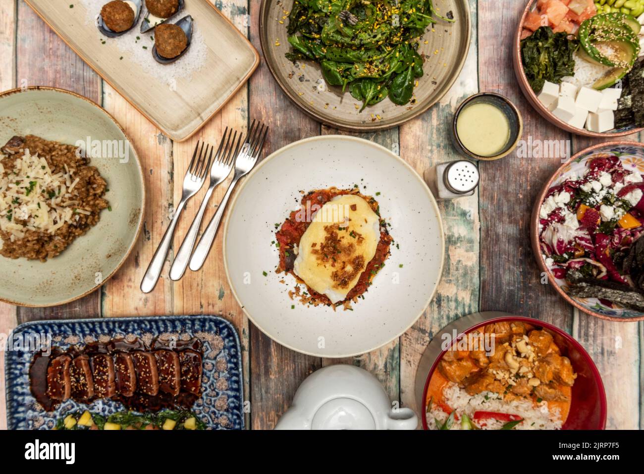 Ricette variegate di moderna cucina internazionale, tataki di tonno rosso con salsa teriyaki, curry di pollo con riso, crocchette di cozze, risotto di funghi, salmone p Foto Stock
