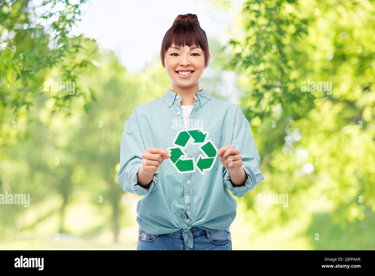 donna asiatica sorridente con un cartello verde di riciclaggio Foto Stock