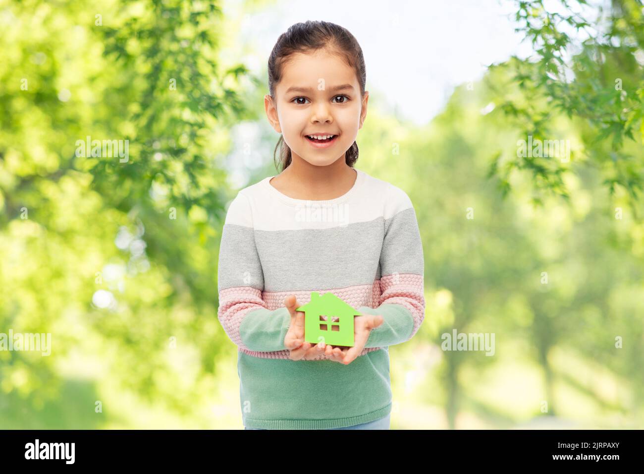 piccola ragazza sorridente che tiene l'icona verde della casa Foto Stock