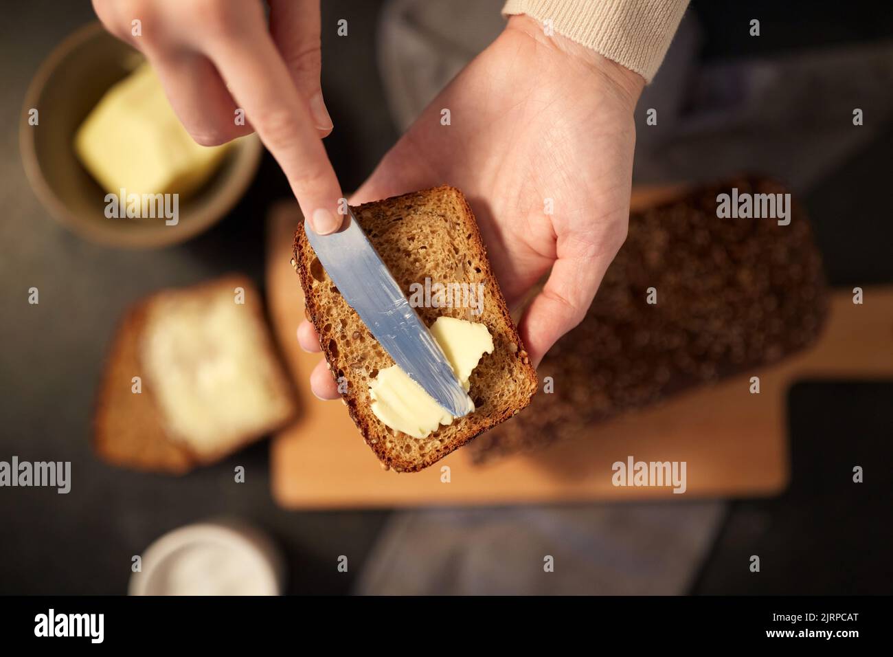 panettiere femmina che spalma il burro sul pane fatto in casa Foto Stock