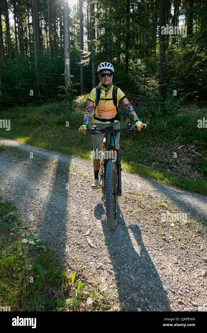 Mountain Biker Riding su strada naturale attraverso la foresta in basso sole e Long Shadows. Zurigo Oberland, Svizzera Foto Stock
