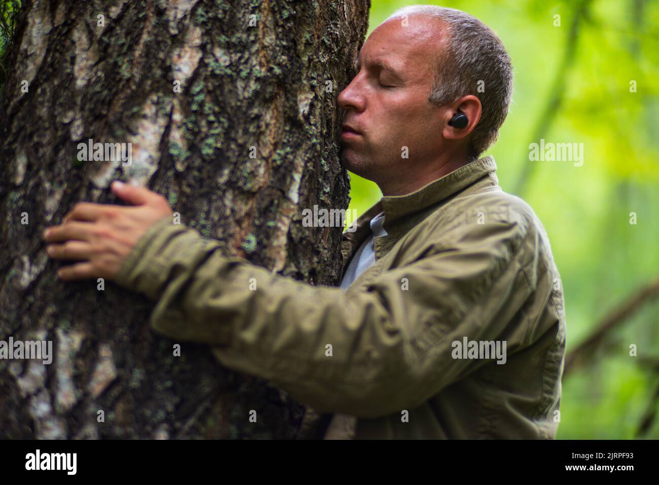 Un uomo abbraccia un albero nella foresta. Abbaio wood. Che si prende cura dell'ambiente. L'ecologia il concetto di salvare il mondo e di amare la natura da parte dell'uomo Foto Stock