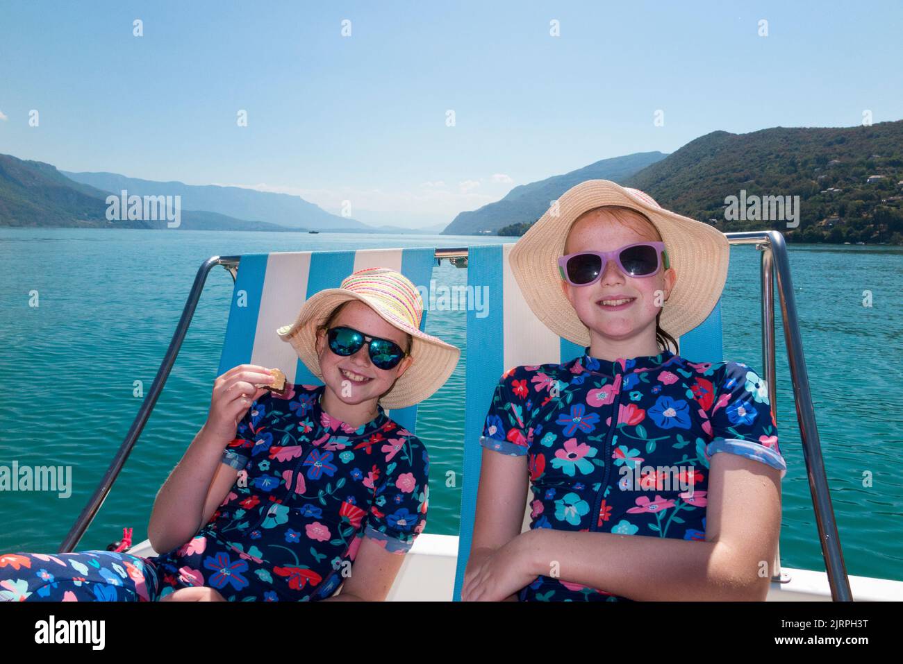 Bambino / bambino / bambini / bambini indossando cappelli e tute rash godendo il sole da un pedalo sul lago Lac du Bourget in Savoia / Savoia, Francia. Giorno estivo limpido e soleggiato con cielo blu. (131) Foto Stock