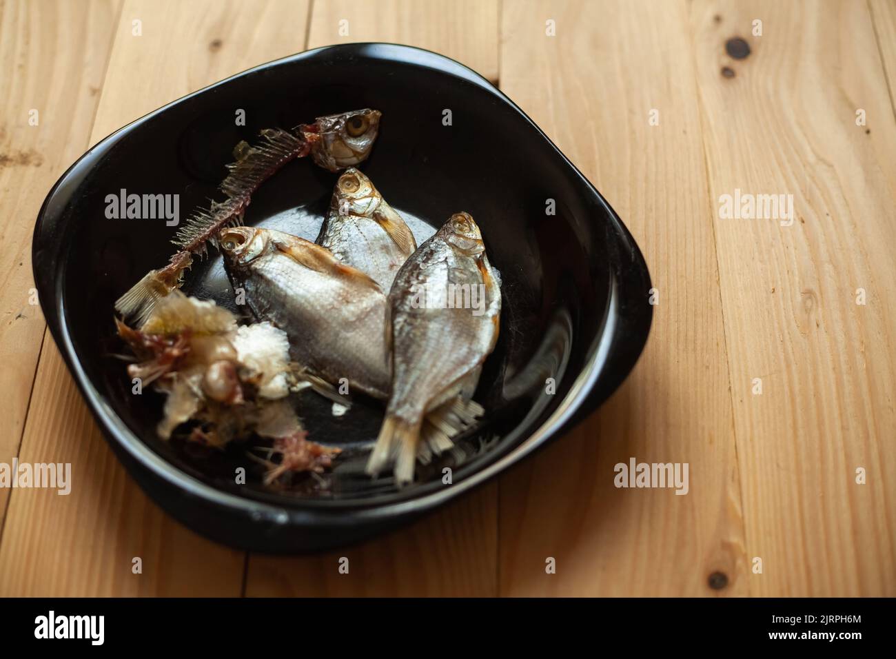 Pesce salato essiccato su un piatto nero. Pesce secco per birra. Foto Stock