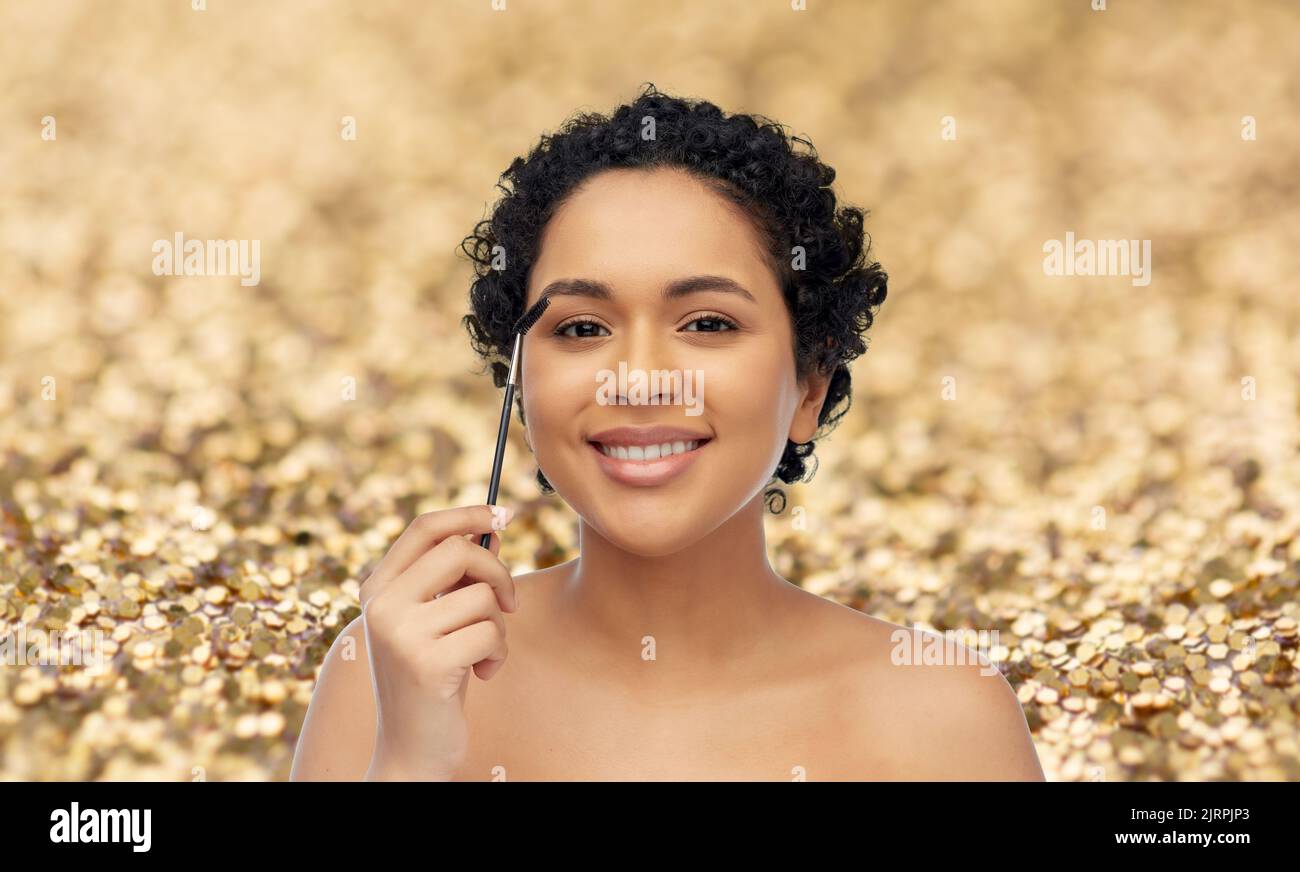 donna afroamericana sorridente con pennello mascara Foto Stock