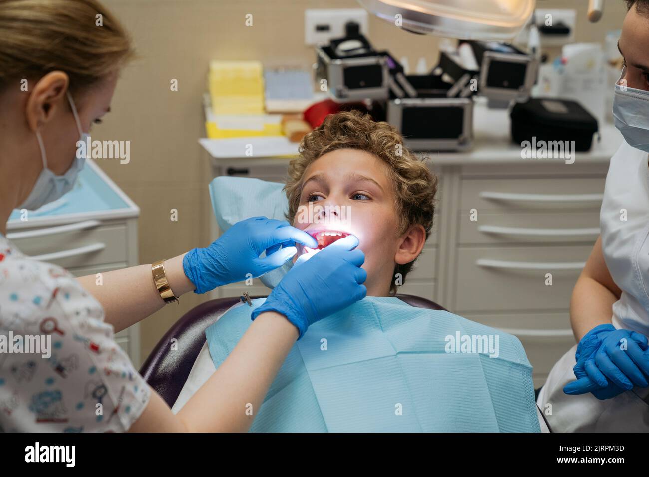 Dentista che controlla i denti del ragazzo in clinica Foto Stock
